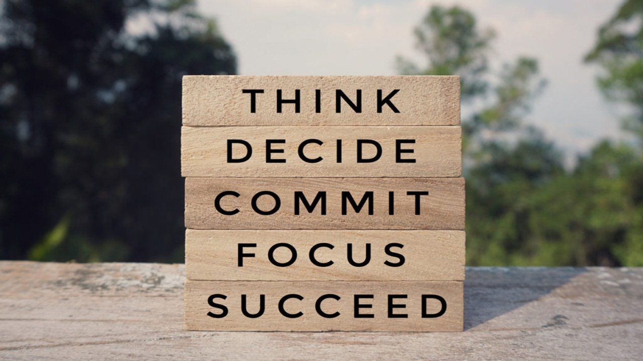 A wooden sign that says think decide commit focus succeed