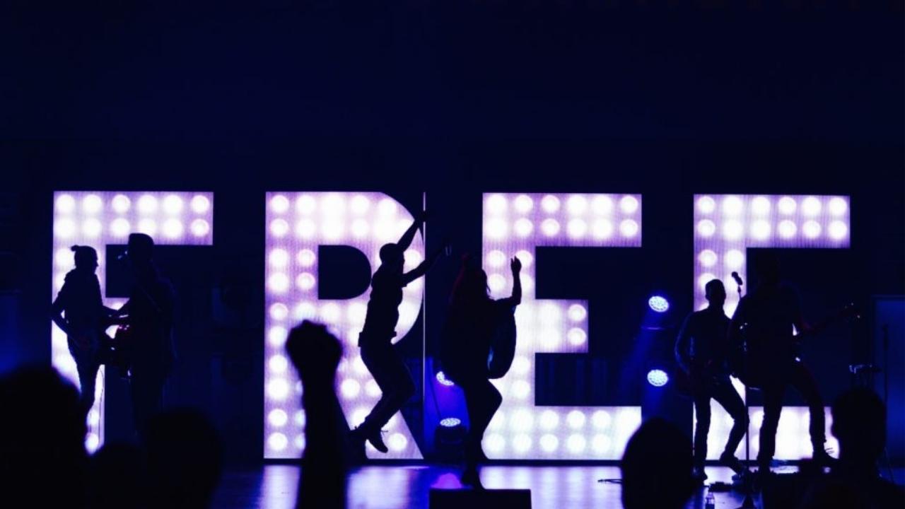 A group of people are dancing in front of a sign that says free.