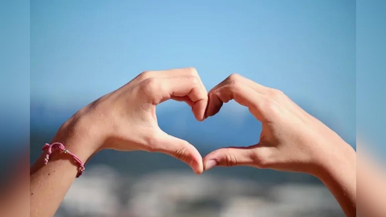 A woman is making a heart shape with her hands.