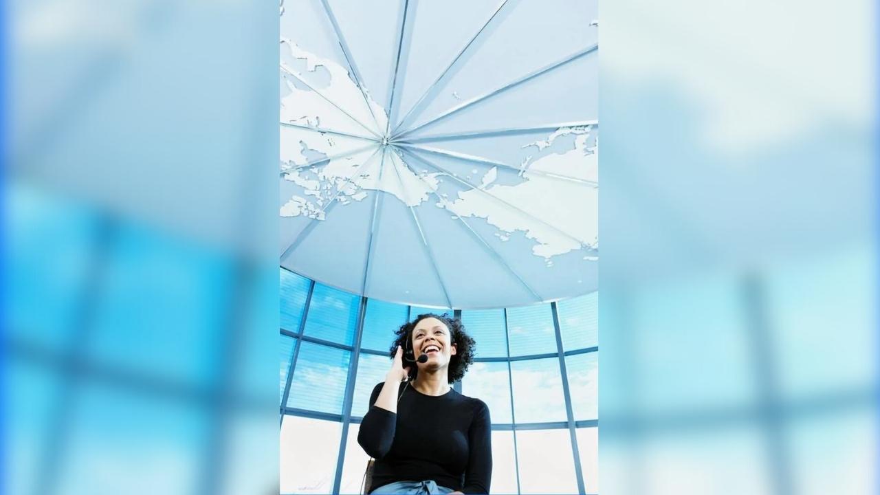 A woman is talking on a cell phone in front of a large window.