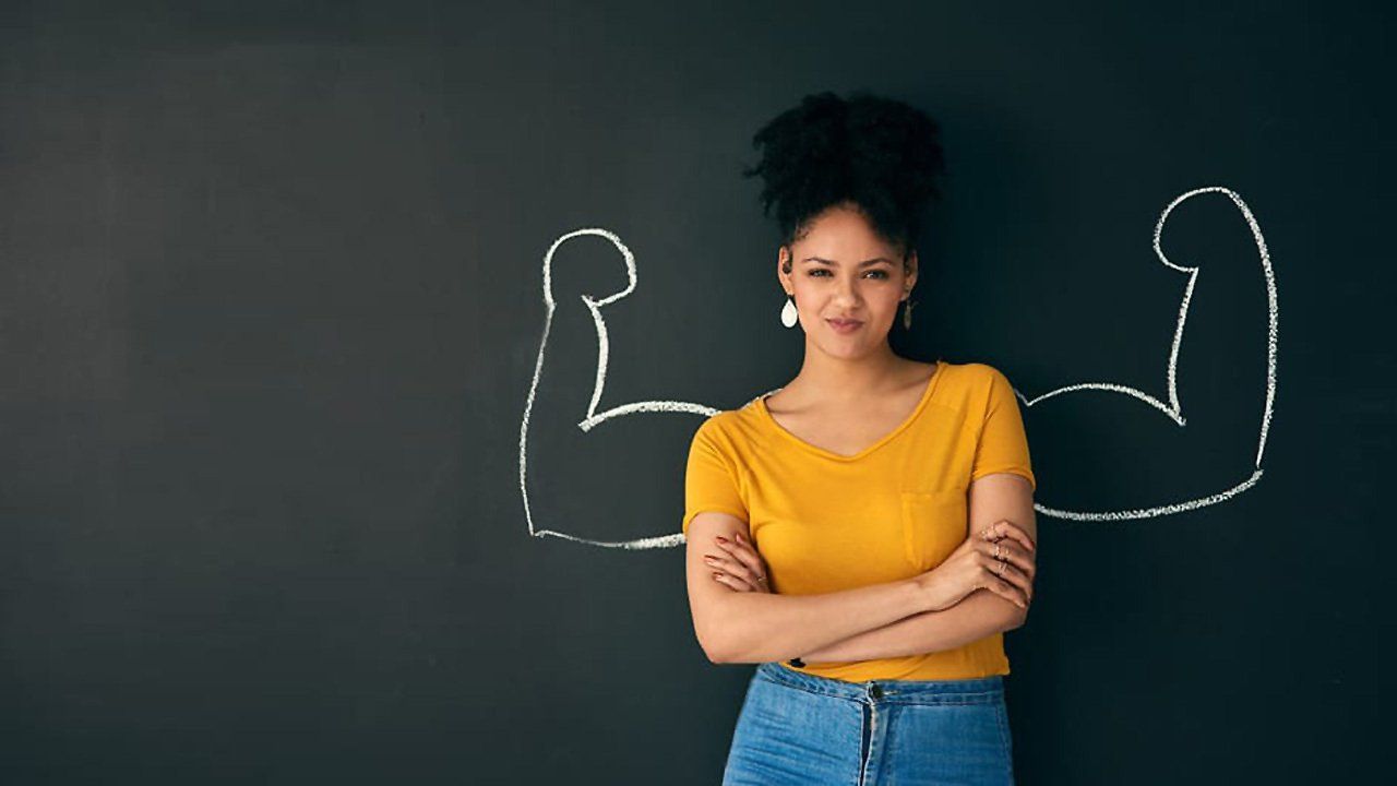 A woman is standing in front of a blackboard with a drawing of her arms drawn on it.