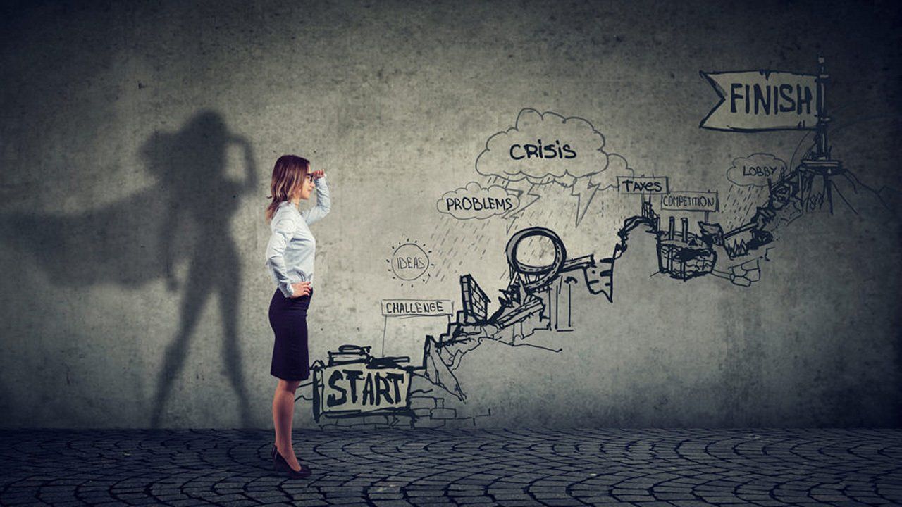 A woman is standing in front of a wall with a drawing of a superhero on it.