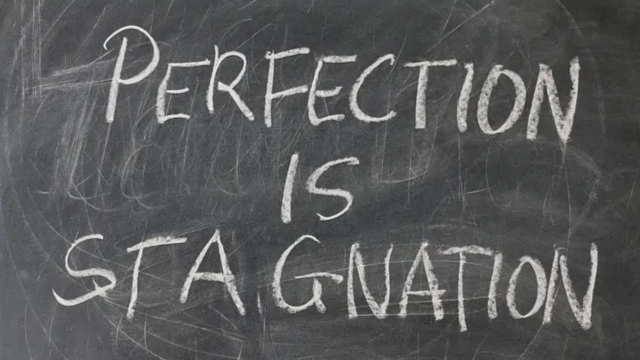 A blackboard with the words perfection is stagnation written on it