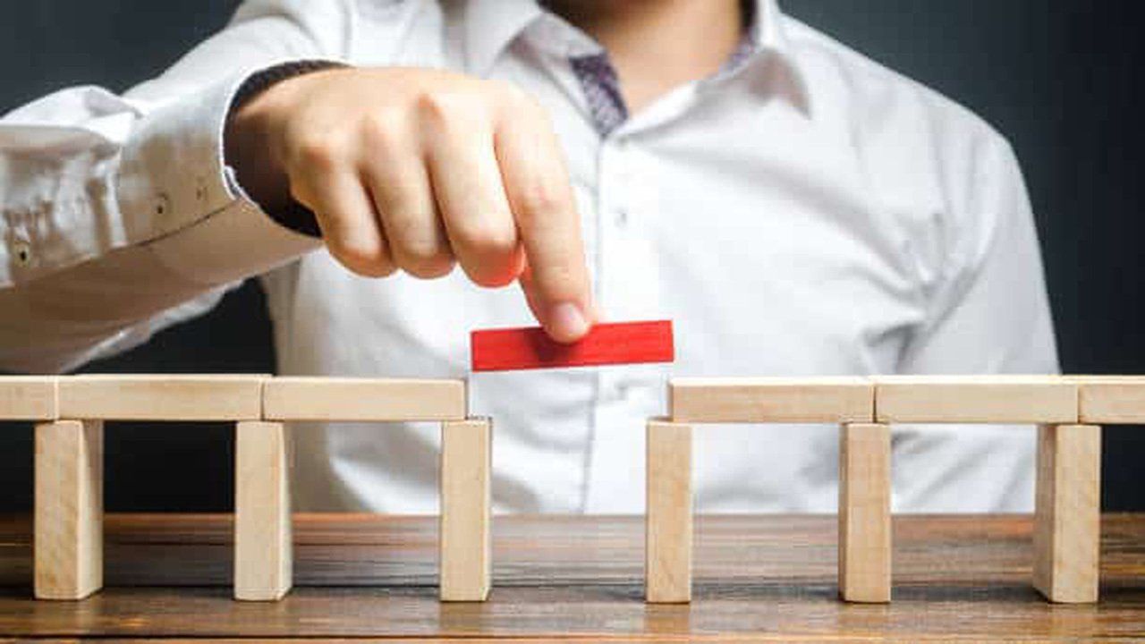 A man is building a bridge out of wooden blocks.