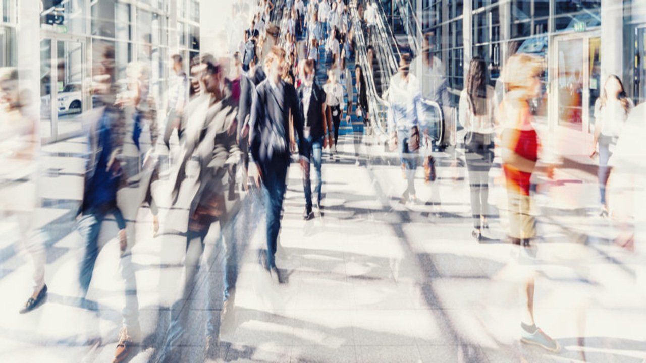 A blurry picture of a crowd of people walking down a city street.