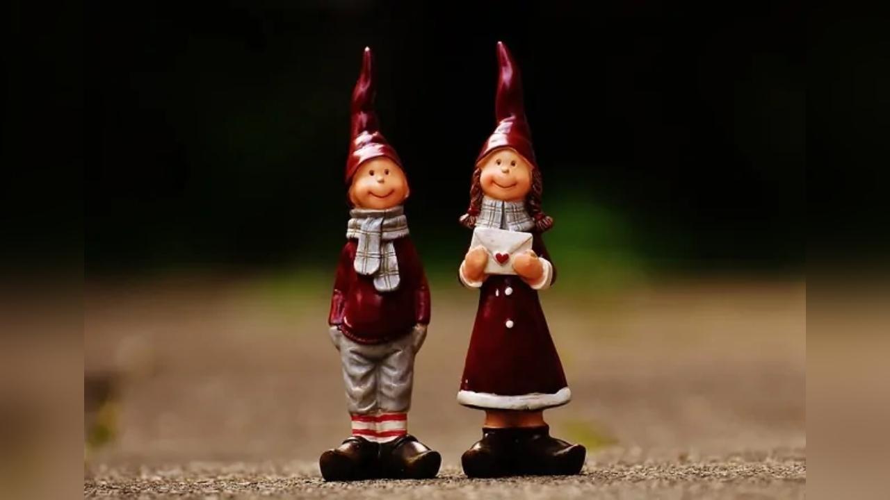 Two christmas figurines , a boy and a girl , are standing next to each other.