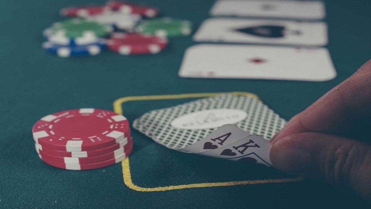 A person is playing a game of poker with cards and chips on a table.