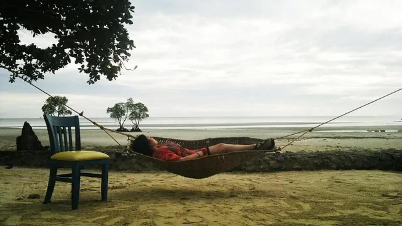 A woman is laying in a hammock on the beach