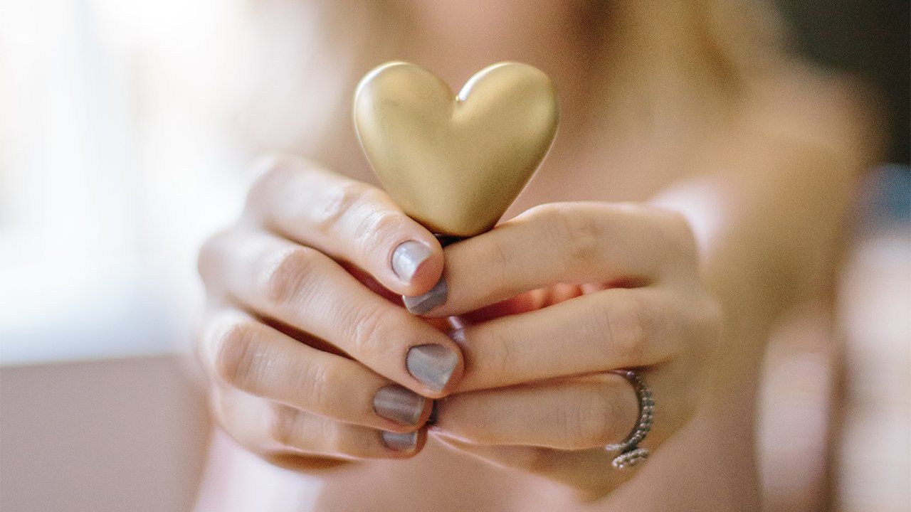 A woman is holding a gold heart in her hands.