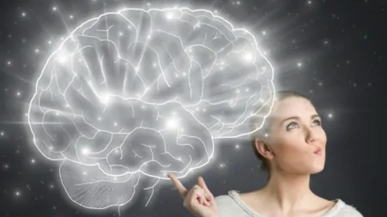 A woman is pointing up at a drawing of a brain.