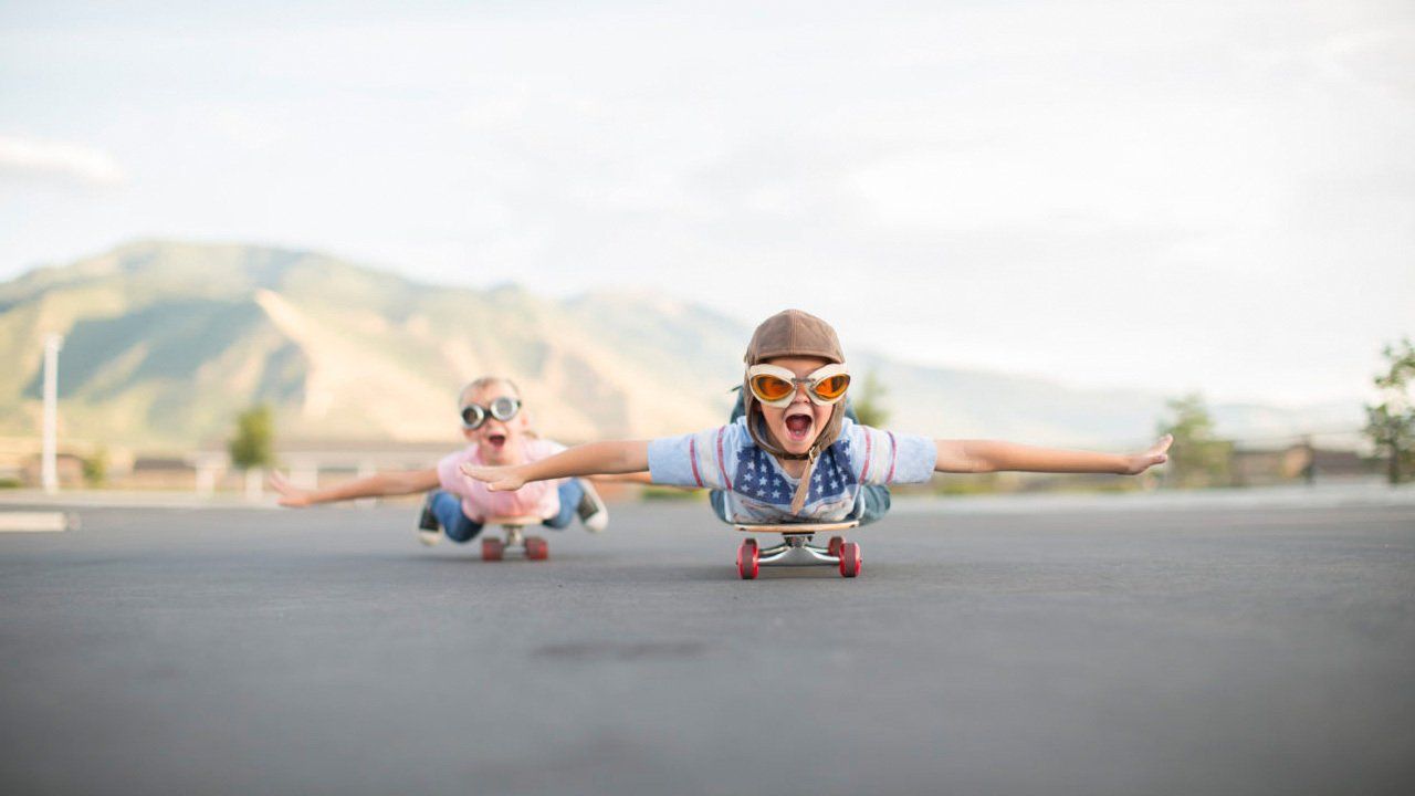 A boy and a girl are riding skateboards down a street.