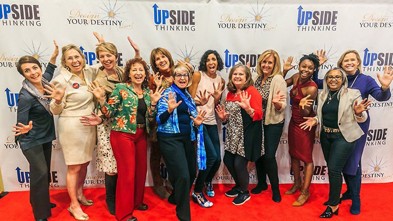 A group of women are posing for a picture on a red carpet.