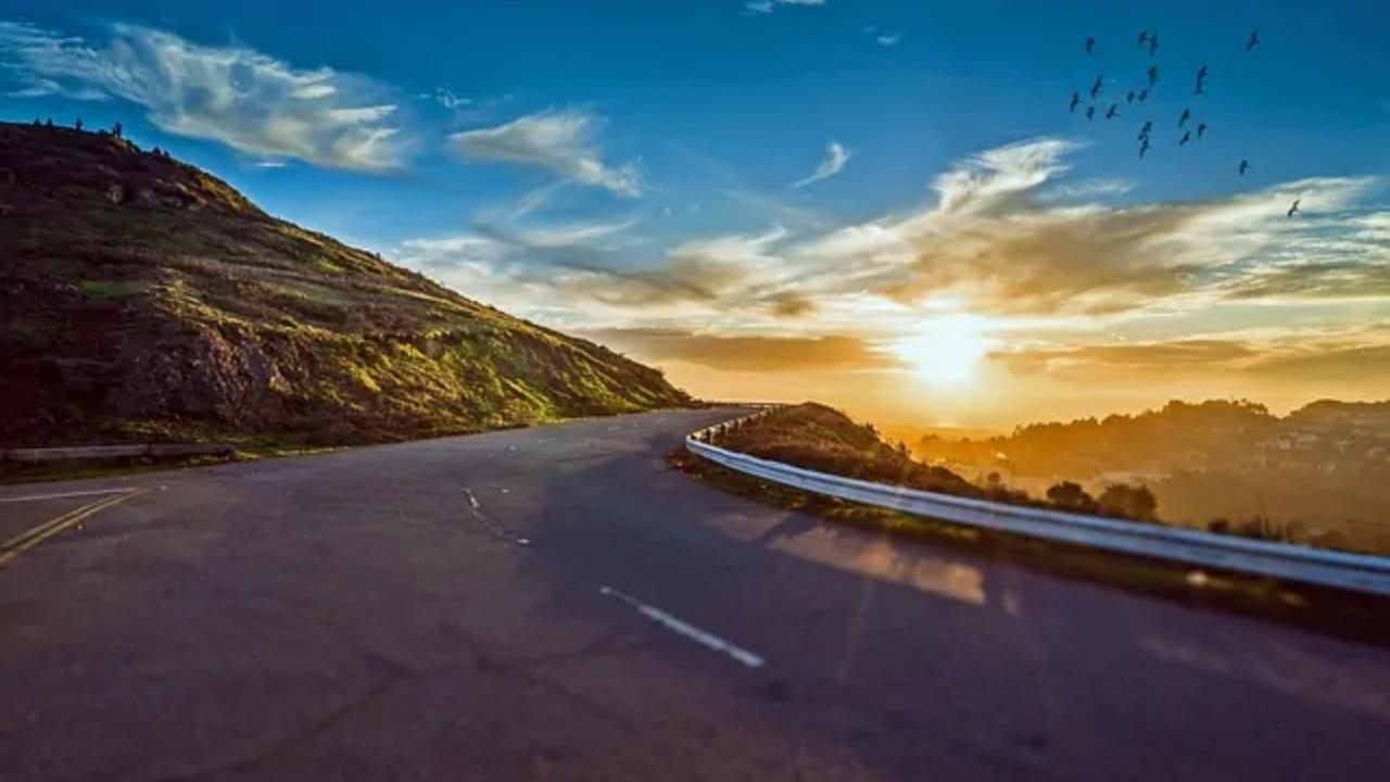 A curvy road with a sunset in the background.