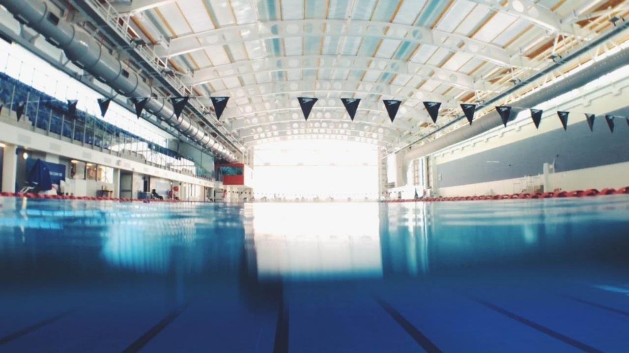 A large indoor swimming pool with flags hanging from the ceiling.