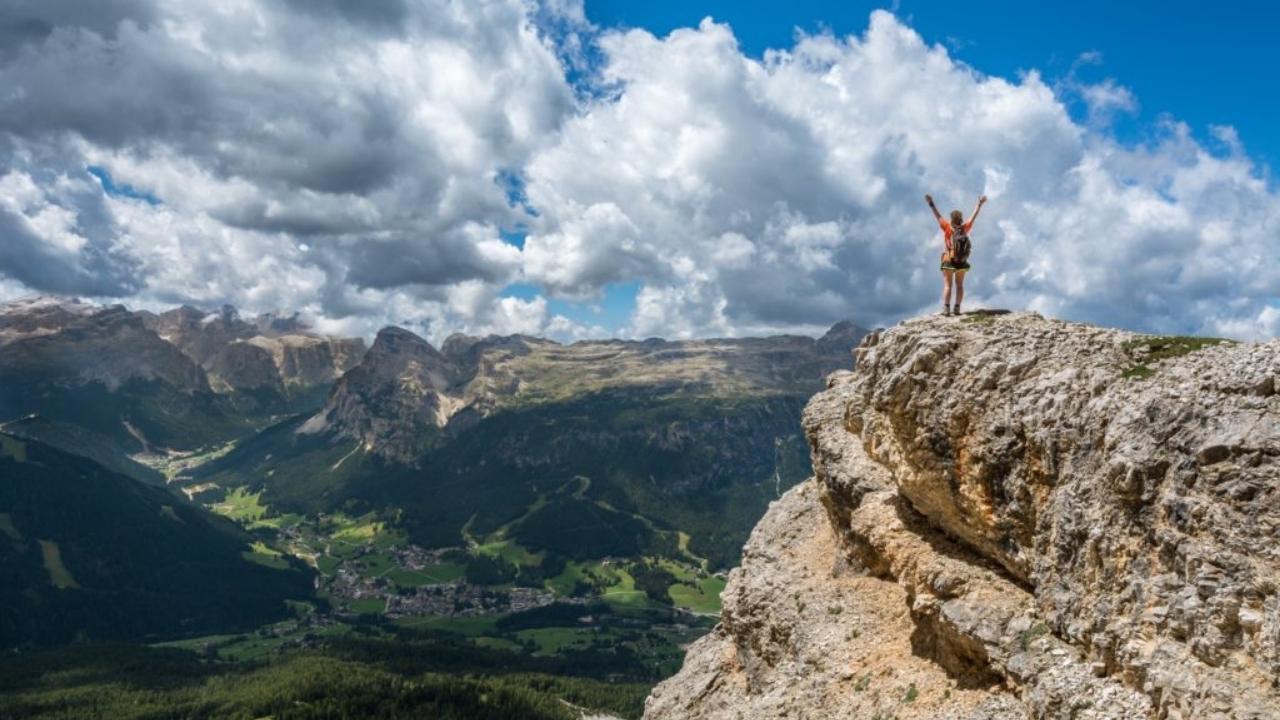 A person is standing on top of a mountain with their arms in the air.