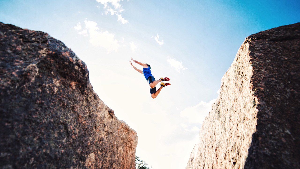 A person is jumping off a cliff into the air.