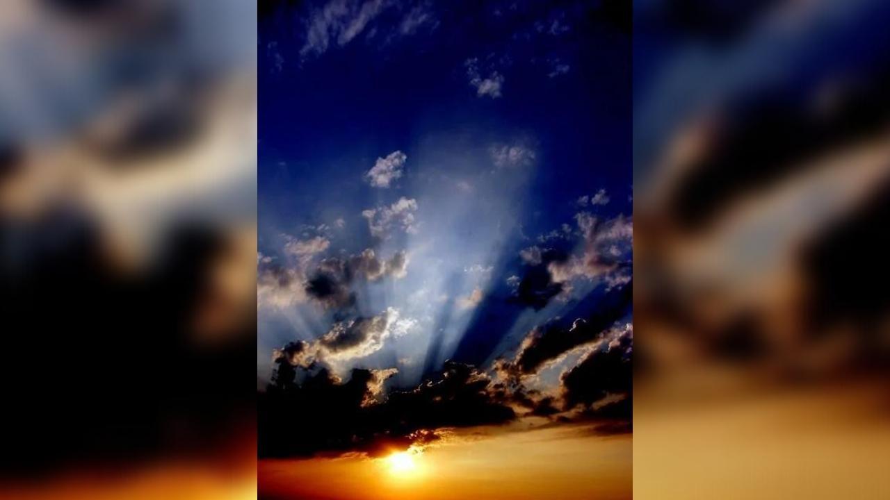 The sun is shining through the clouds at sunset