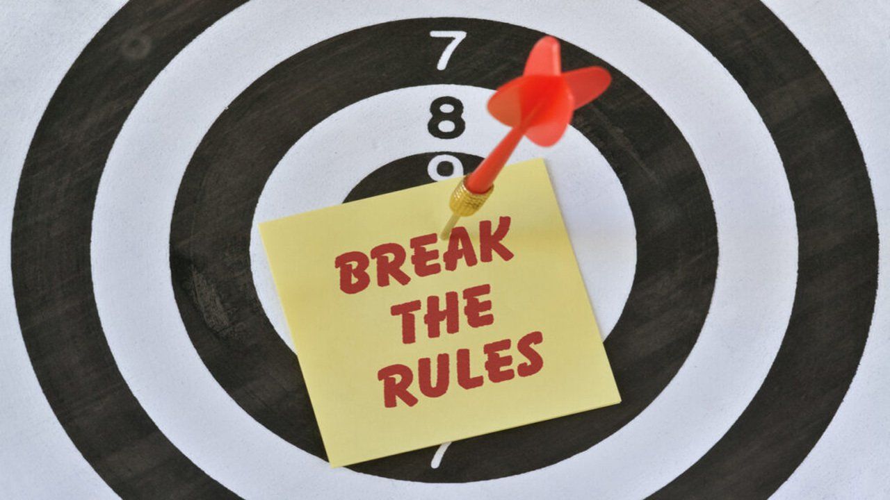 A dart board with a sticky note that says break the rules