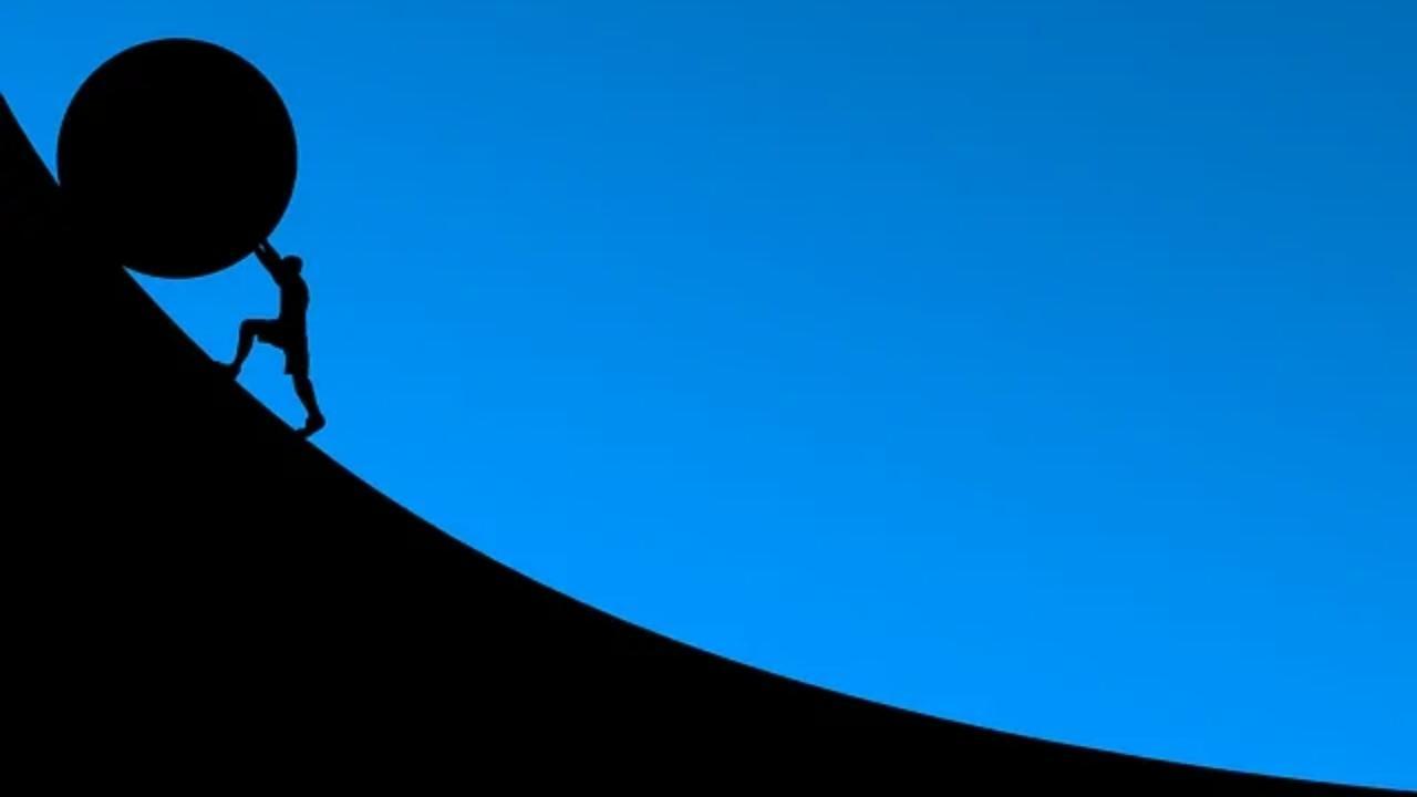 A man is pushing a large rock up a hill.