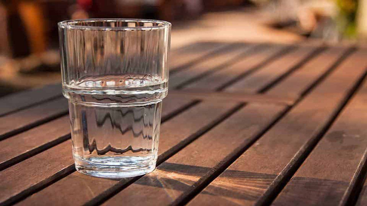 A glass of water is sitting on a wooden table.