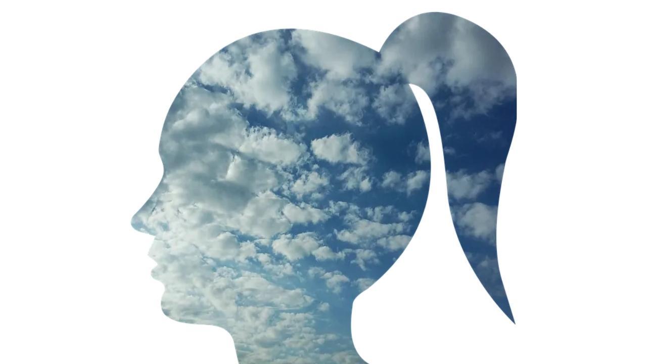 A silhouette of a woman 's head with clouds in the background.