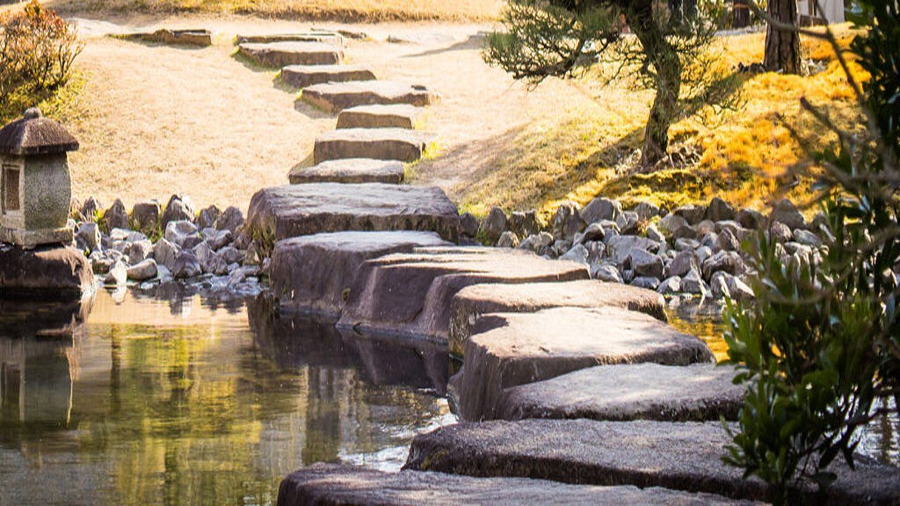 A stone bridge over a river in a park.