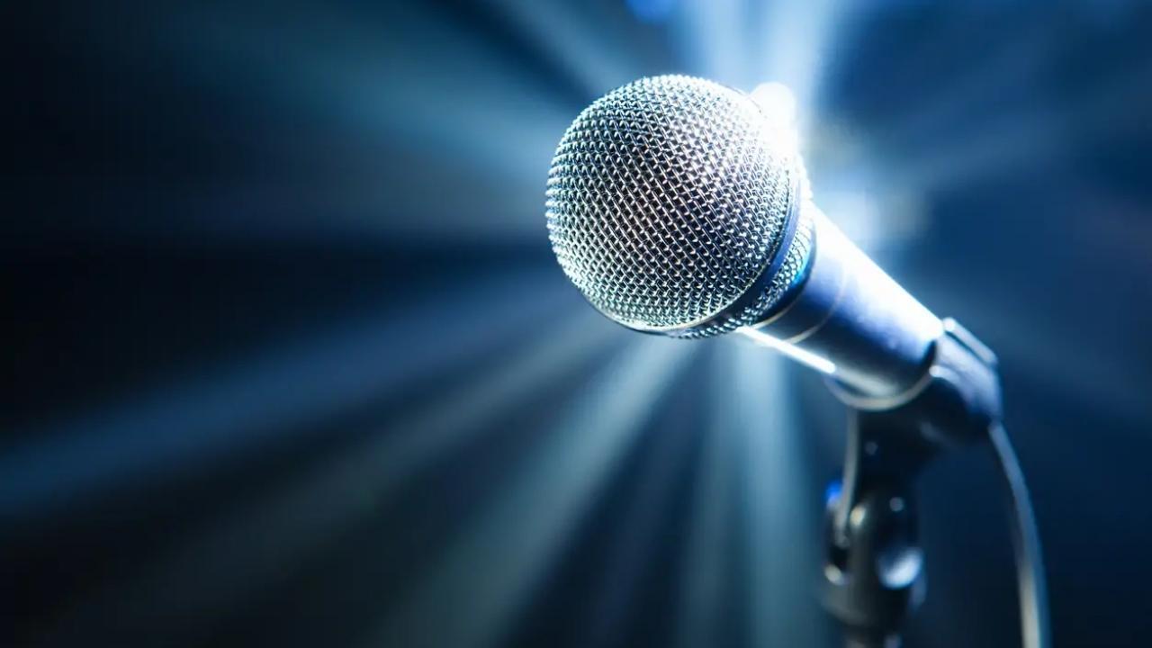 A microphone is sitting on a stand in front of a blue light.