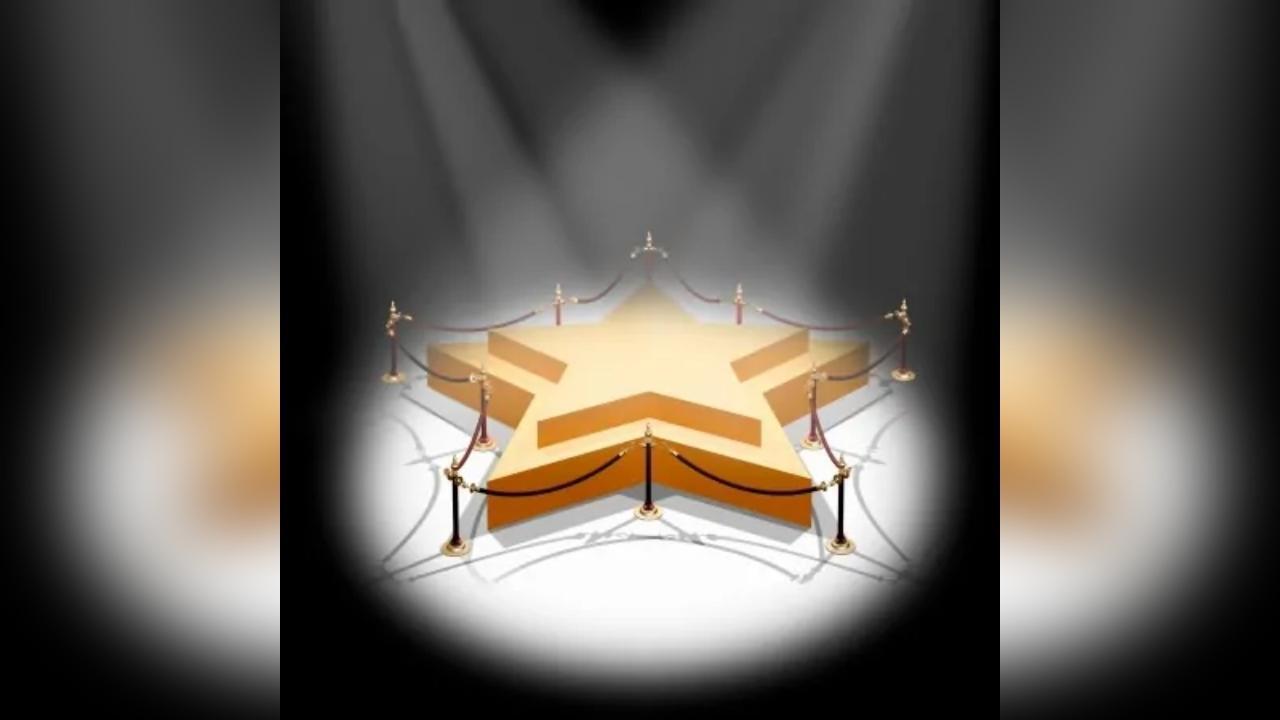 A gold star is on a stage with a spotlight shining on it.