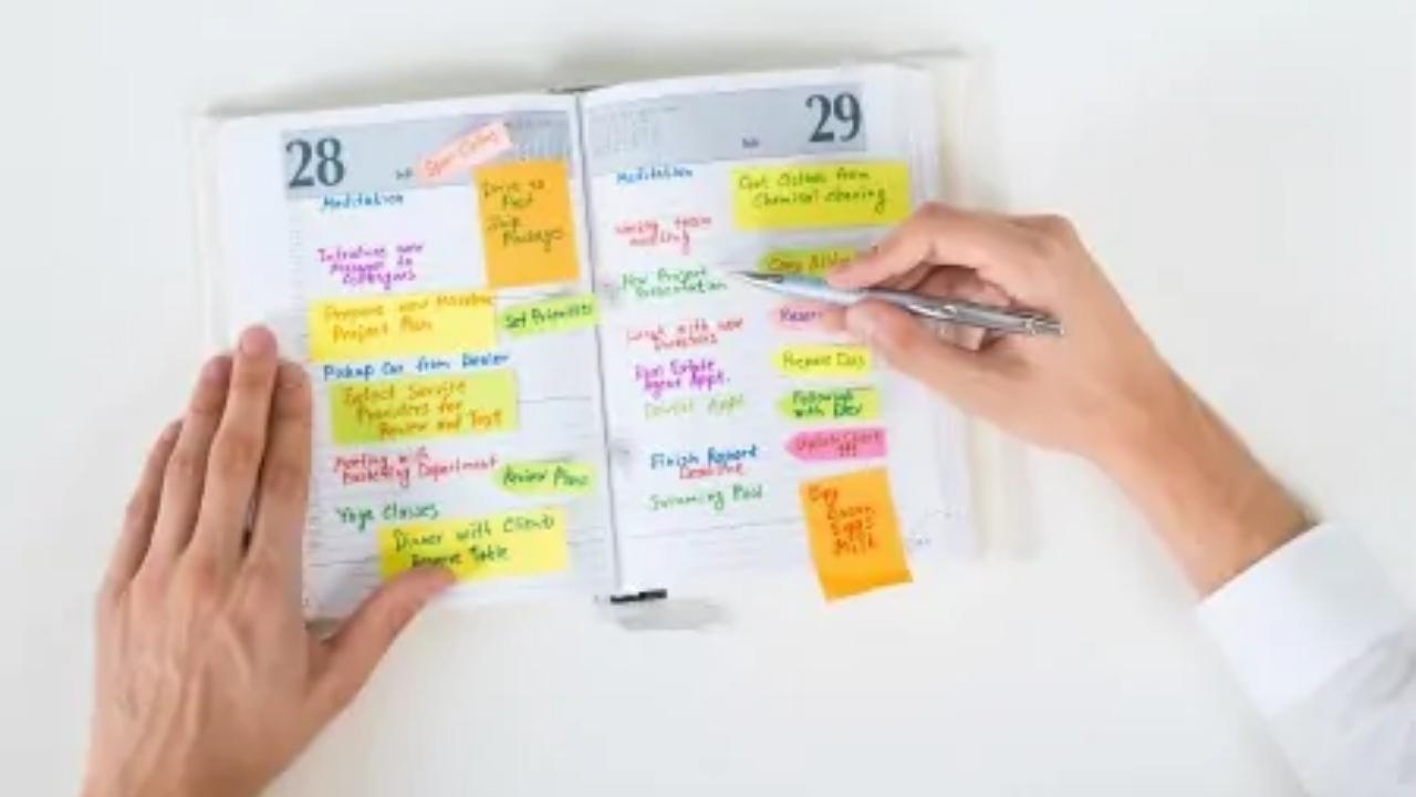 A person is writing in a calendar with sticky notes.