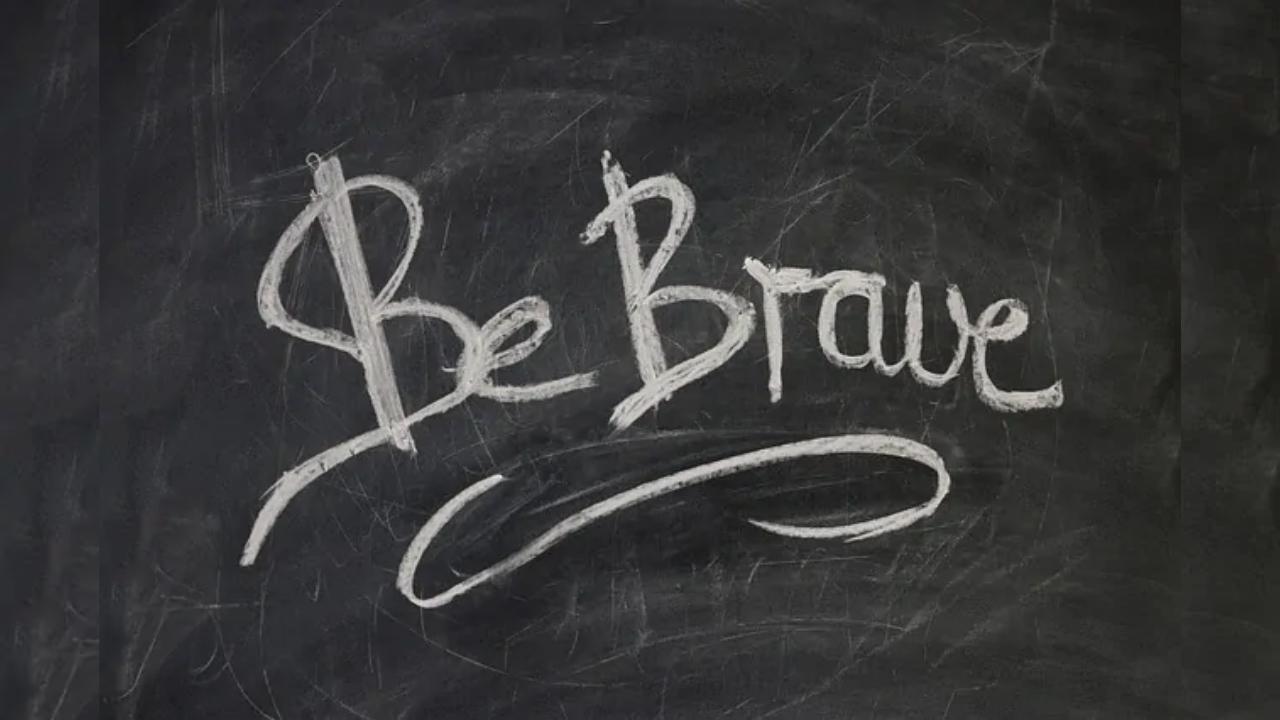 The word be brave is written in white chalk on a blackboard.
