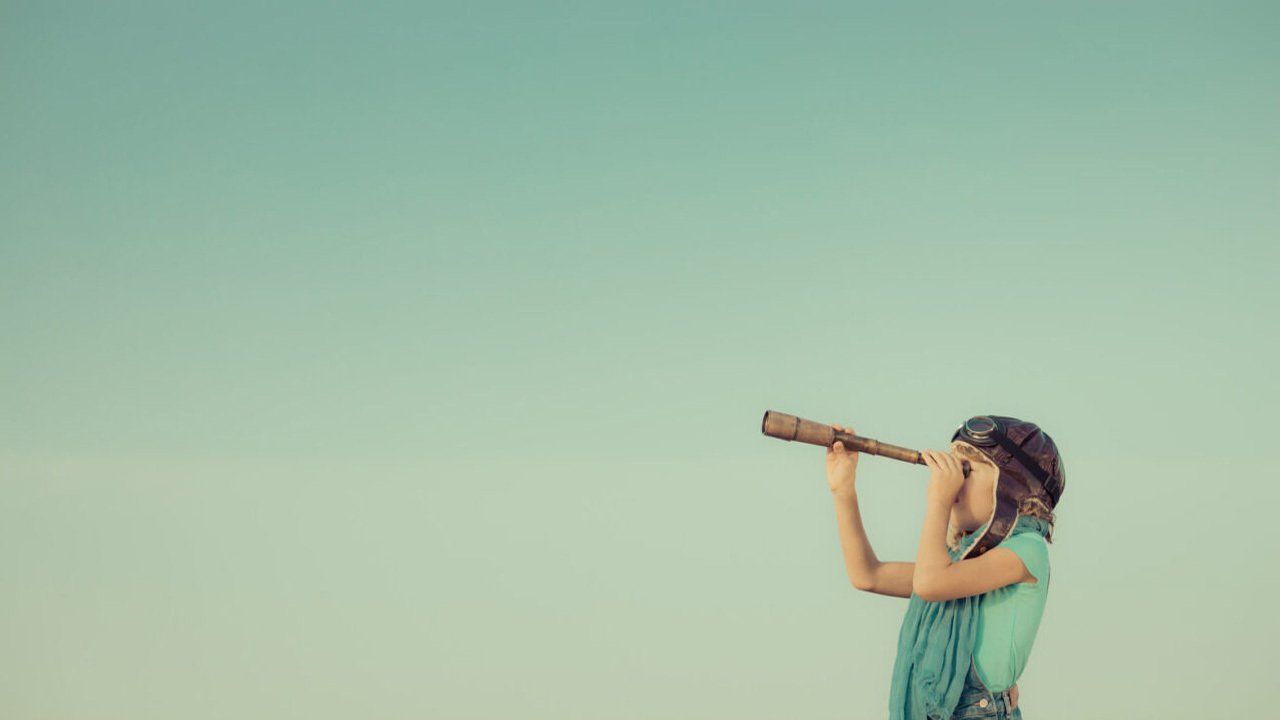 A young girl is looking through a telescope at the sky.
