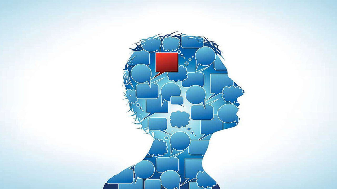 A silhouette of a person 's head made of speech bubbles with a red speech bubble in the middle.