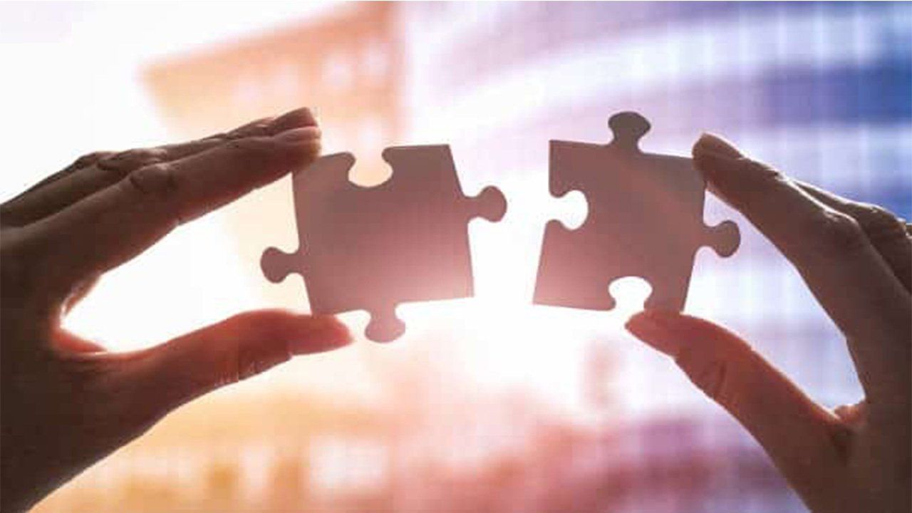 A person is holding two puzzle pieces in their hands.