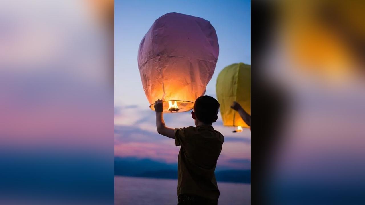 A boy is holding a lantern in the air.