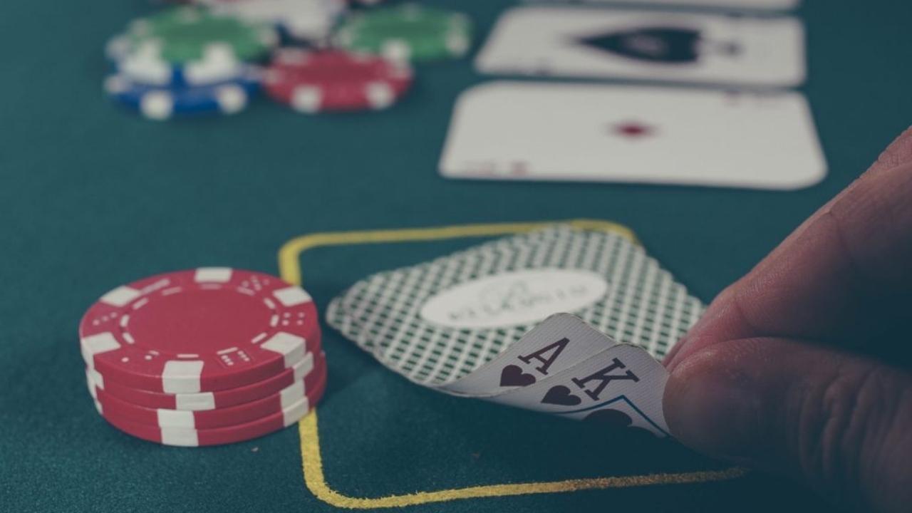 A person is playing a game of poker on a green table.