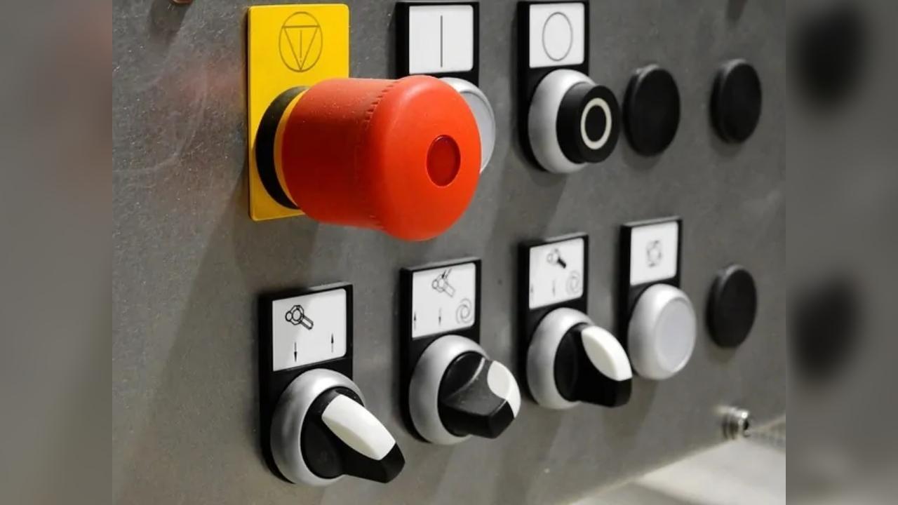 A bunch of buttons on a wall with a red button in the middle