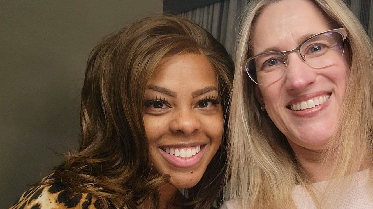 Two women are posing for a picture together and smiling for the camera.
