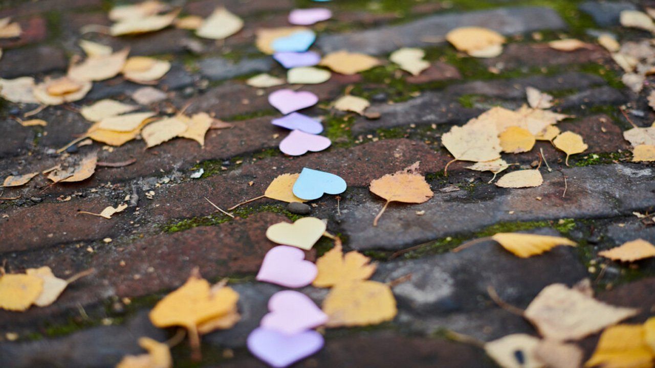 A row of hearts and leaves on a brick sidewalk.