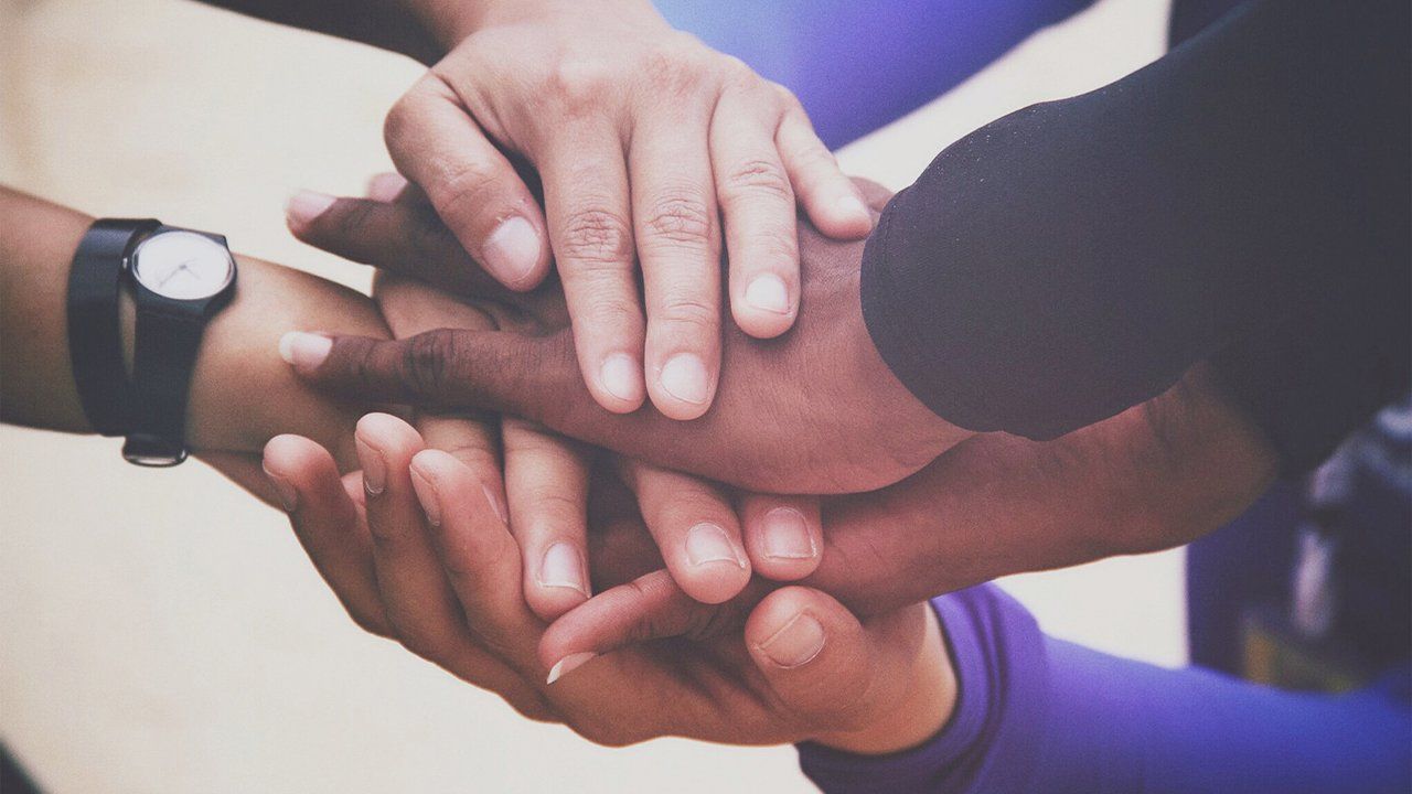 A group of people are putting their hands together.