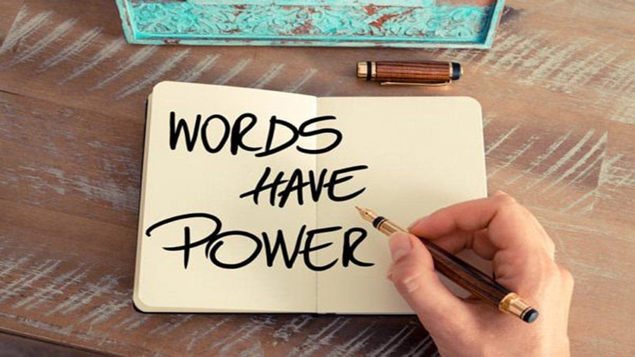A person is writing in a notebook that says `` words have power ''.