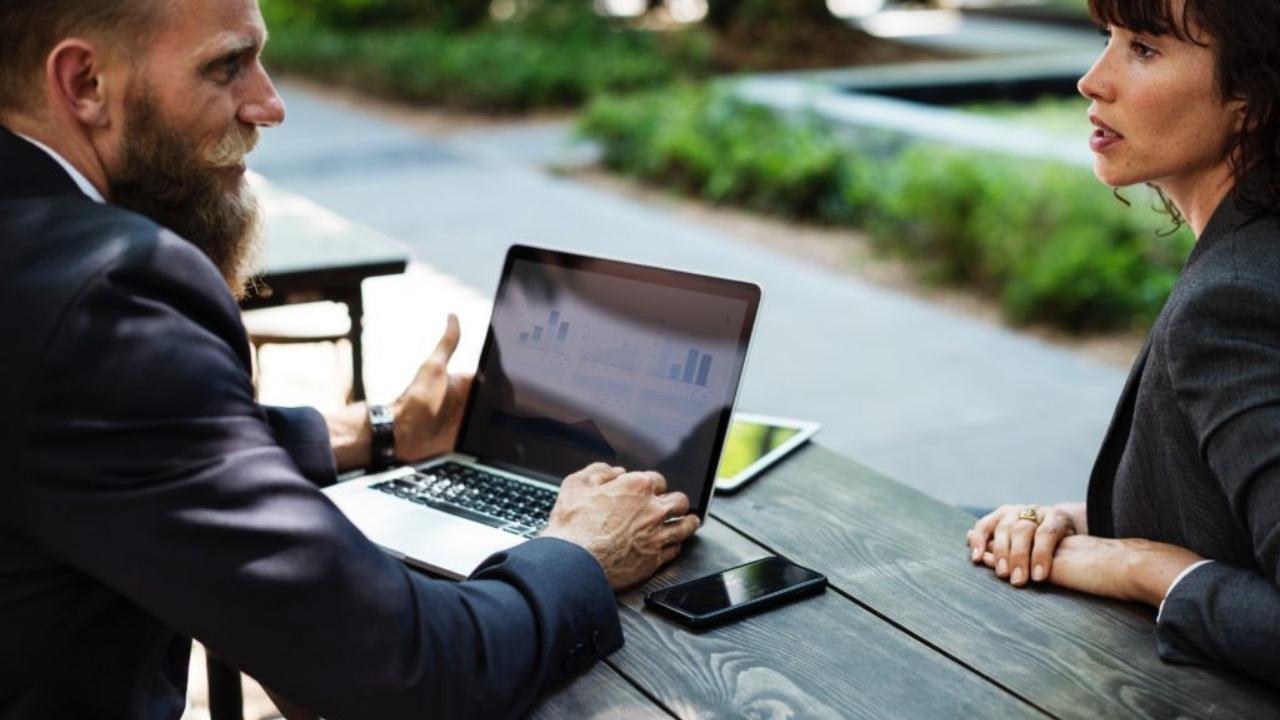 A man and a woman are sitting at a table with a laptop.