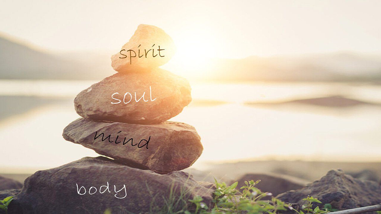 A stack of rocks with the words spirit , soul , mind , body written on them.
