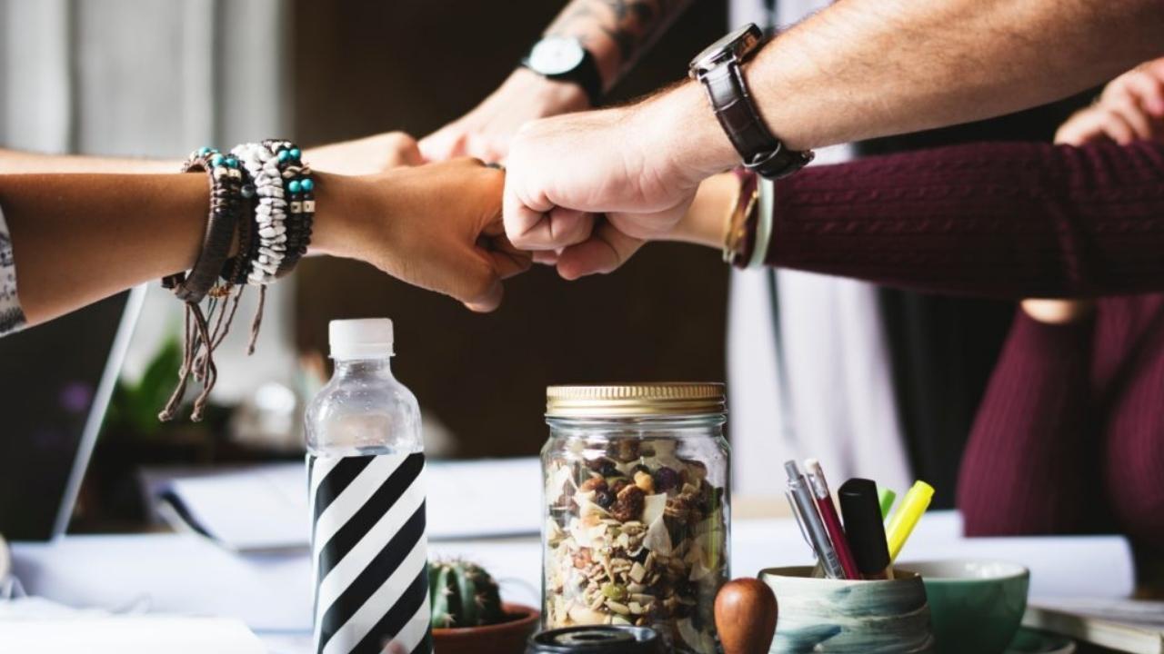 A group of people are putting their hands together in a huddle.
