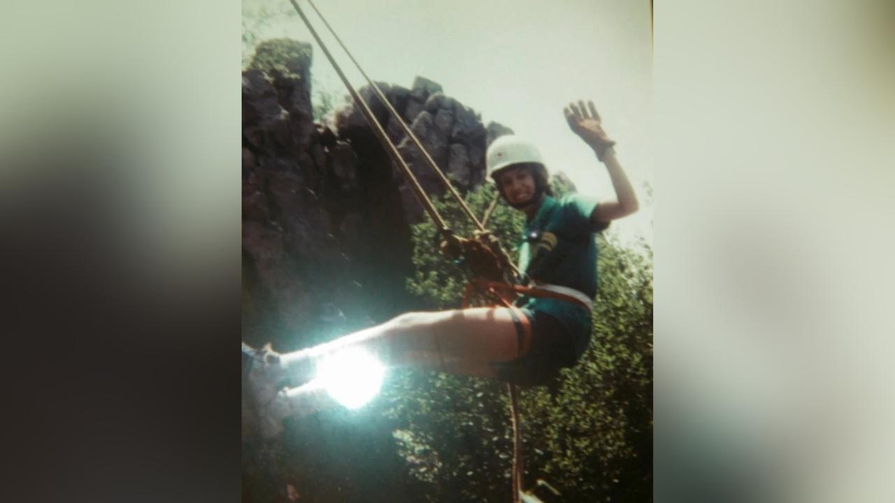 A person is climbing a rope up a mountain.