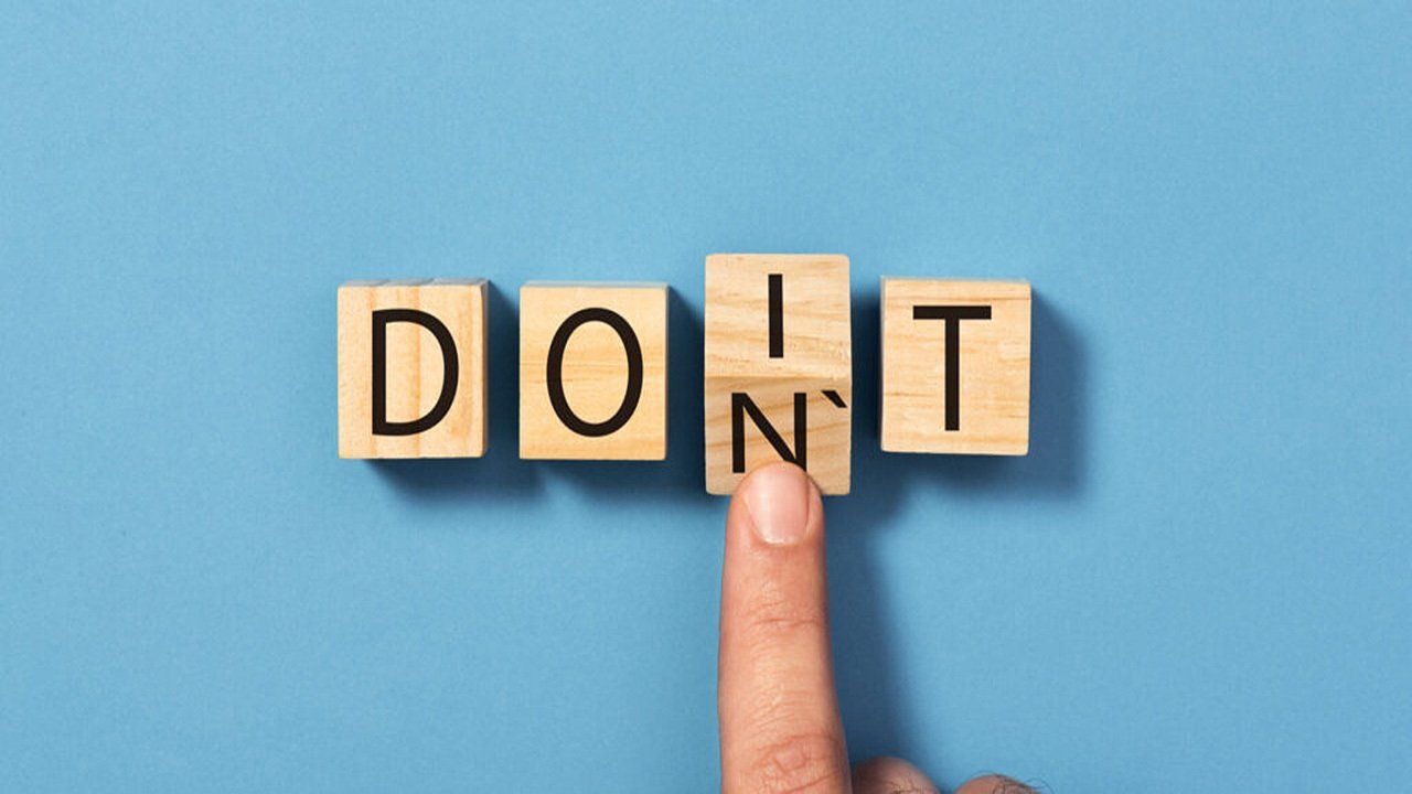 A person is holding a wooden block with the word do n't written on it.