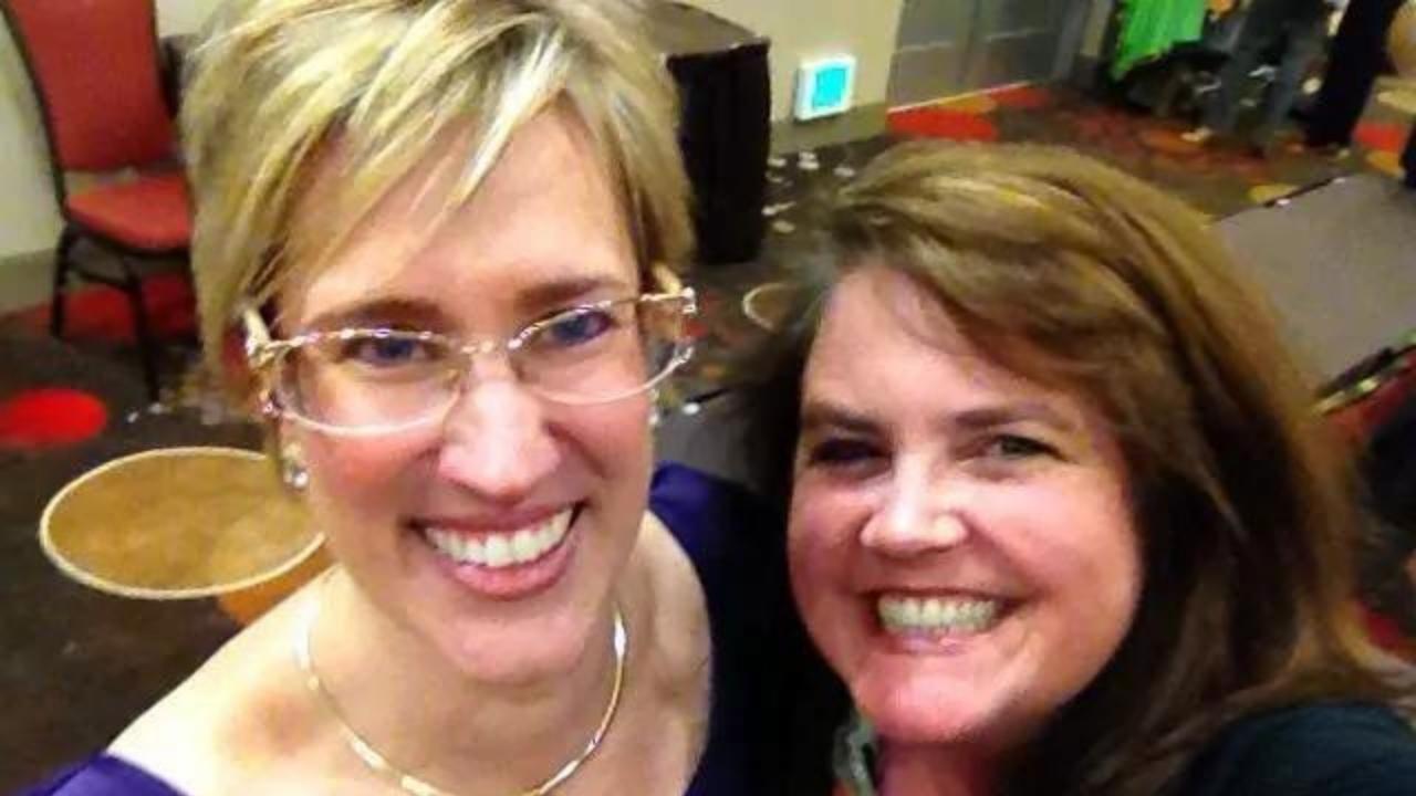Two women are posing for a picture and smiling for the camera