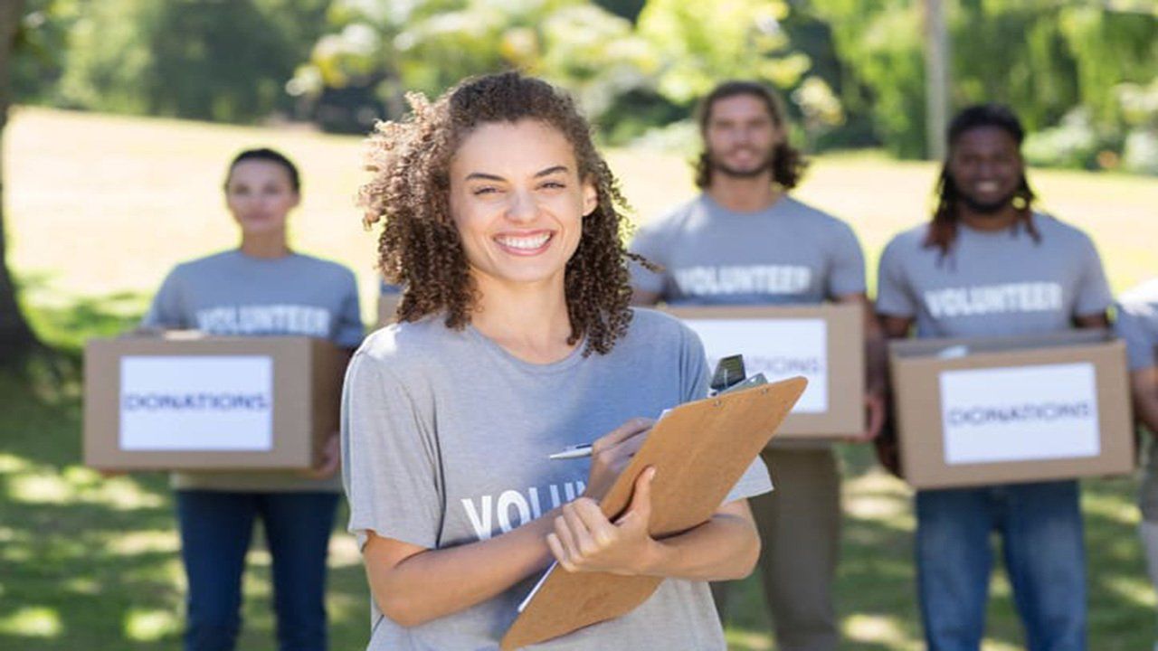 A group of volunteers are holding boxes and a clipboard.