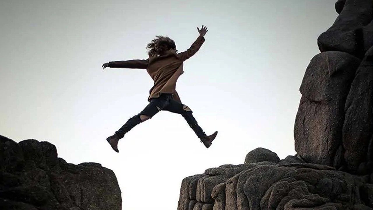 A person is jumping over a rocky cliff.