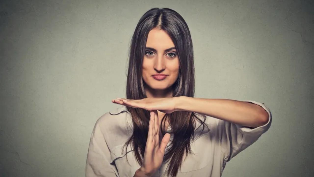 A woman is making a stop sign with her hands.