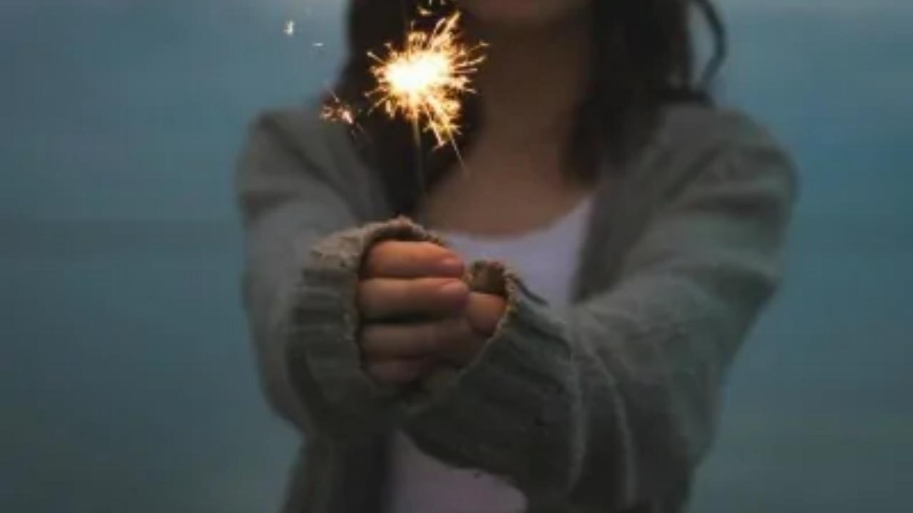 A woman is holding a sparkler in her hand.